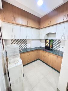 a kitchen with white appliances and wooden cabinets at Nivasa-Crafted with love in Ghaziabad +5 photos