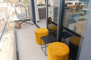 Un balcón con dos taburetes amarillos y una silla. en Santa Ocean View, en Mindelo