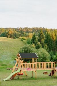 a wooden playground with a slide in a field at PUŹNIAKÓWKA in Czarna