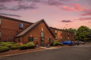 a brick building with a car parked in a parking lot at HomeTowne Studios & Suites by Red Roof Greensboro in Greensboro