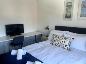 a bedroom with a bed with a desk and a television at Home2Home Meadow Close in East Kilbride