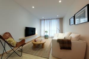 Una sala de estar con un sofá, una mesa y un televisor. en Vita Homes by Upper Luxury Housing, en Santiago de Compostela