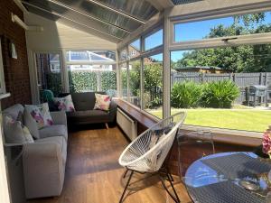 a screened in porch with a couch and a chair at Home2Home Meadow Close in East Kilbride