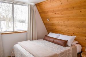 a bed in a room with a wooden wall at Peaceful A-Frame Cabin - Great Views with Hot Tub in Kremmling
