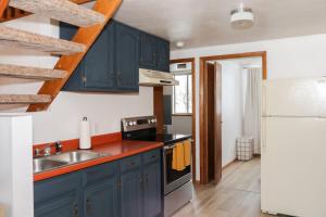 a kitchen with blue cabinets and a sink and a refrigerator at Peaceful A-Frame Cabin - Great Views with Hot Tub in Kremmling +46 photos