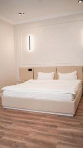 a large white bed in a room with a wooden floor at Jagalau Hotel in Balqash +6 photos