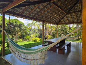 a hammock on a patio with a table and bench at Cabana das Mandalas in Itacaré