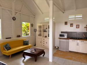 a living room with a yellow couch and a table at Kaz'Arawak in Sainte-Rose