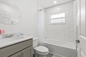a white bathroom with a toilet and a sink at Coosa Dr in Port Saint Lucie +34 photos
