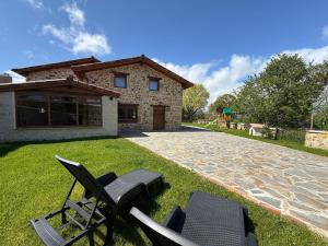 a group of chairs sitting on the grass in front of a house at Casa Rural la Marina in Las Rozas de Valdearroyo