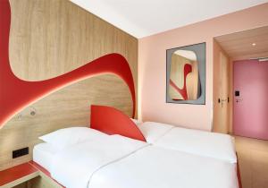 a bedroom with a white bed with a red headboard at Prize by Radisson, Munich Airport in Hallbergmoos +39 photos