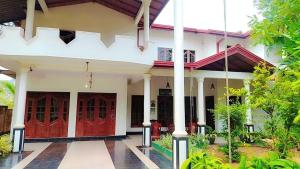 a white house with red doors and a courtyard at Ayurora home in Dambulla