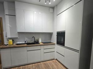 a white kitchen with white cabinets and a wooden floor at Apartament Oaza Jastrzębia Góra in Jastrzębia Góra +4 photos
