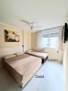 a bedroom with two beds and a window at Pitangueiras - Shopping in Guarujá +30 photos