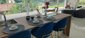 a dining room table with blue chairs and a kitchen at Villa Flora Lake Como - Villa con piscina in Asso
