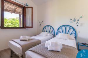 two twin beds in a room with a window at La Bouganville - House with garden and sea view in Geremèas