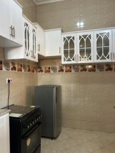 a kitchen with white cabinets and a stainless steel refrigerator at Comfort home in Msaranga +12 photos