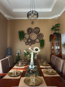 a dining room with a long table with plates on the wall at Comfort home in Msaranga