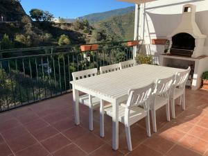 Una mesa blanca y sillas en un balcón con vista. en Piso el Zorro, 40m2 Dachterrasse, en Istán