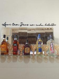 a shelf with alcohol bottles and glasses on it at Casa do Marquinho in Aparecida