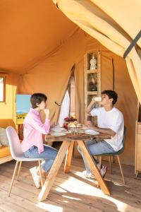 a man and a woman sitting at a table in a tent at Etna Glamping in Milo