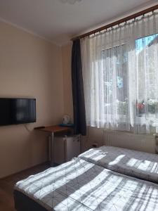 a bedroom with a bed and a television and a window at pokoje STIFADO in Międzyzdroje