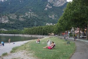 a group of people sitting on the grass near a lake at Casa VACANZE MAGNOLIA in Vercurago