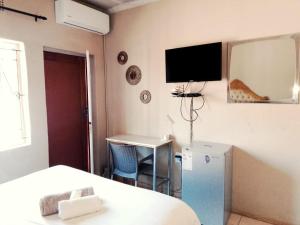 a bedroom with a bed and a desk and a tv on the wall at KO'THABENG GUESTHOUSE in Lebowakgomo