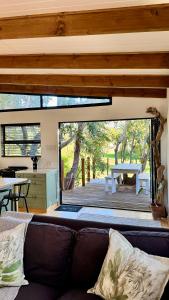 a living room with a couch and a view of a deck at Blue Gum Tree Cottage in Dagbreek