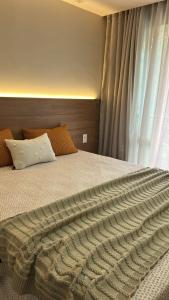 a bedroom with a bed with a pillow and a window at Vista Azul Apart Hotel in Frutal