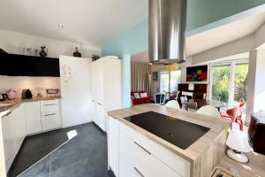 una cucina con armadi bianchi e una grande isola di Maison lumineuse avec jardin à 50m de la mer a Larmor-Plage Altre 38 foto