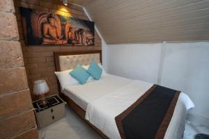 a small bedroom with a bed with blue pillows at The Tranquil Cabana - kandy in Rattanadeniya
