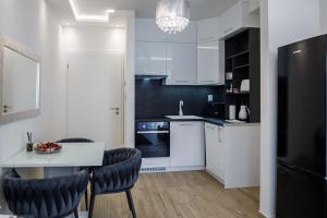 a kitchen with white cabinets and a table and chairs at Rebany Apartman 2 Free parking, Central Location in Debrecen