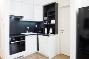 a kitchen with white cabinets and a black wall at Rebany Apartman 2 Free parking, Central Location in Debrecen