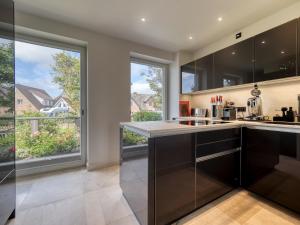 a kitchen with black cabinets and large windows at Haus Watt`n Blick in List +32 photos