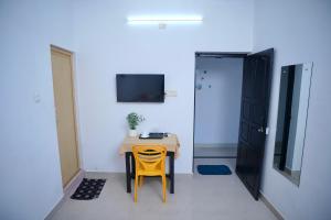 a small table and a yellow chair in a room at Roomify Inn in Trivandrum