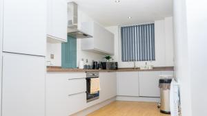 une cuisine avec des armoires blanches et une fenêtre dans l'établissement Cozy Modern Apt MCR City Centre, à Manchester 20 autres photos