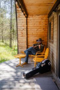 a man sitting on a bench on the porch of a cabin at A Frame Hot Tub Couple's Getaway in Island Park