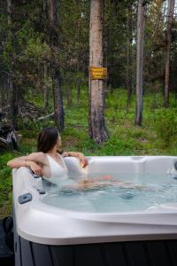 a woman sitting in a bath tub in the woods at A Frame Hot Tub Couple's Getaway in Island Park