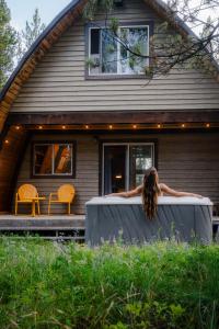 a woman in a hot tub in front of a house at A Frame Hot Tub Couple's Getaway in Island Park +39 photos