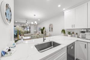 a white kitchen with a sink and a couch at Coquina Beach 2C condo in Sanibel