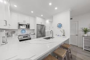 a kitchen with white cabinets and a large white counter at Coquina Beach 2C condo in Sanibel