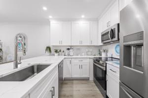 a white kitchen with stainless steel appliances and white cabinets at Coquina Beach 2C condo in Sanibel