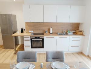 a kitchen with white cabinets and a table with chairs at Living OH43 in Illmitz