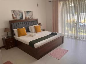 a bedroom with a large bed with yellow and orange pillows at Silina Airport Residence & Transit Hotel in Katunayaka
