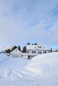 a snow covered yard with a house at Sentrumsnær sokkelleilighet in Bardu