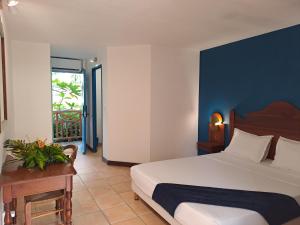 ein Schlafzimmer mit einem Bett und einem Tisch und einem Fenster in der Unterkunft Studio Capucine in Sainte-Anne