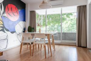 ein Esszimmer mit Tisch und Stühlen und einem großen Fenster in der Unterkunft Fliphaus Gregoria Perez 3500 'A' - 1 Bd Patio & BBQ Colegiales in Buenos Aires
