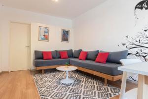 ein Wohnzimmer mit einem blauen Sofa mit roten Kissen in der Unterkunft Fliphaus Gregoria Perez 3500 'A' - 1 Bd Patio & BBQ Colegiales in Buenos Aires