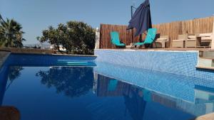 a swimming pool with blue chairs and an umbrella at J&L Glamping in La Presa